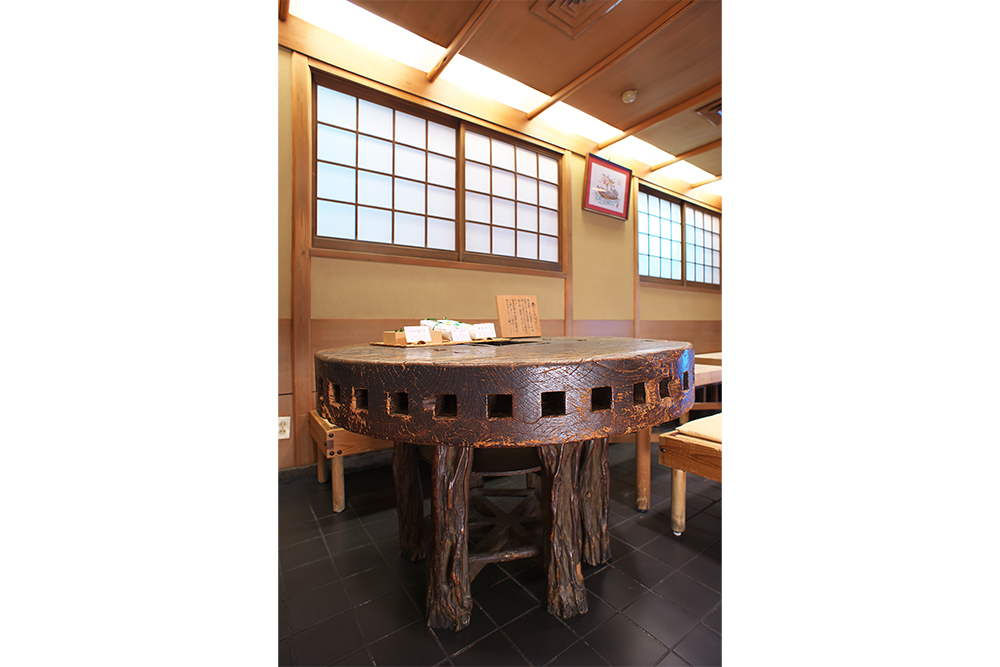 店を70 年見守り続けるテーブルは、水車に使われていたと思しき歯車に脚を付けた年代物のリサイクル品。