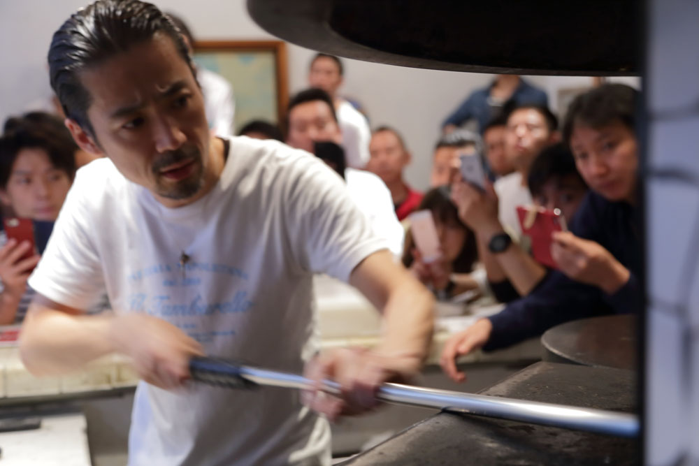 ピッツァパドルにのせた生地を回転させながら、まんべんなく火を入れていく。