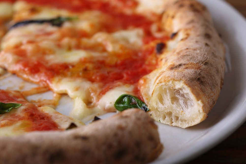 トマトソースとチーズが染み込み、しっとりとしたクラスト。ふっくらとした耳は香ばしくほどよい弾力。