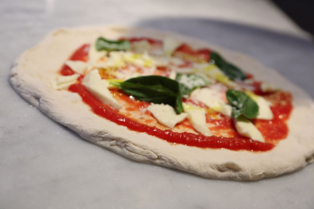 チーズはモッツァレッラ、塩は結晶塩を使用。甘味も酸味もマイルドなトマトソースは自家製。フレッシュバジルをあしらい、オリーブ油をひとわましかける。