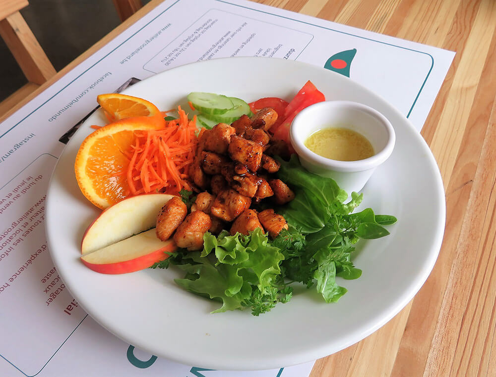 柔らかい鶏肉はケバブのような味付けで、レモン風味のソースもなかなか。ニンジンやキュウリ、サラダ菜のほかにオレンジやリンゴも添えられている