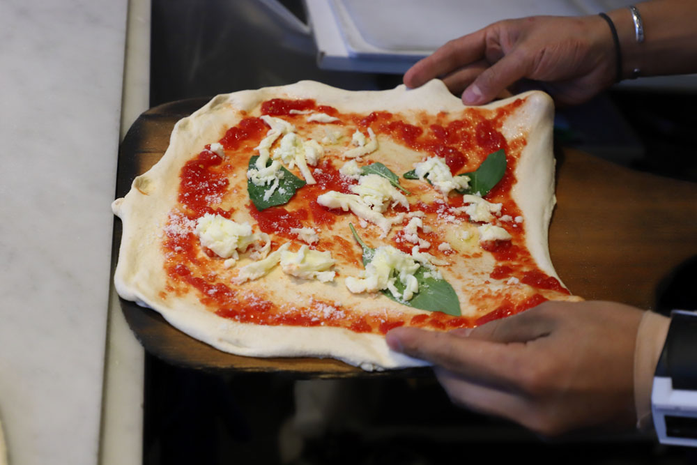 ピッツァパーラの上で、最終的な大きさに伸ばす。円形であることにはこだわらない。あくまでも極力触らずに窯に入れることに意識を向ける。