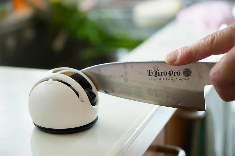 包丁はこまめに研ぐ。シャープナー／貝印社製なら、レバーを下げて吸盤で固定すると片手で研げる。ダイヤモンド歯の「粗目」「仕上げ」の順で、１週間に1～2回研ぐ。