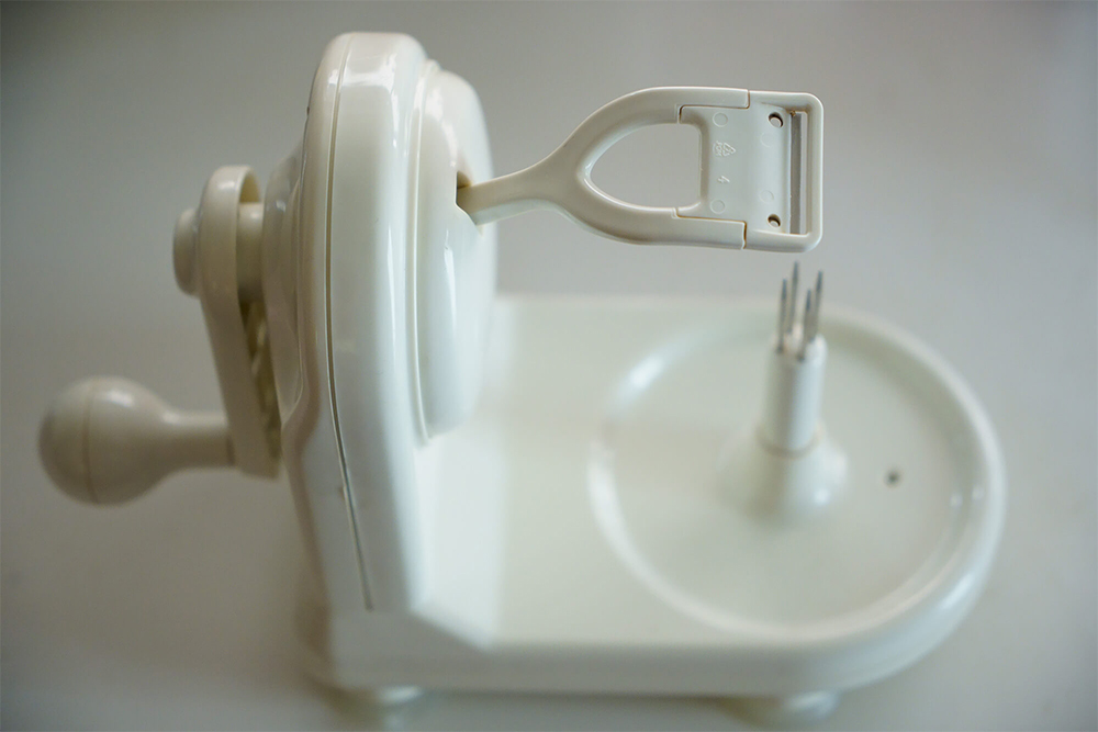 活用している皮剥き器のひとつで、アップルピーラー／パール金属社製。 本体24×12×17㎝。吸盤付き。 突起にリンゴを刺し、左手でハンドルを回す。