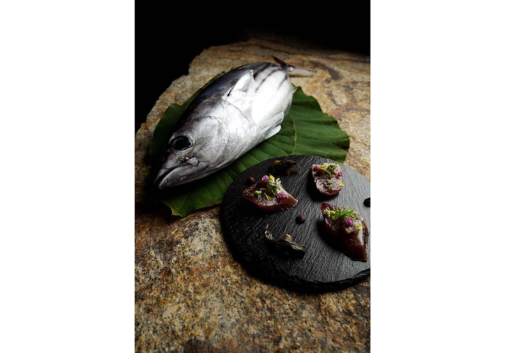 「星のや東京」浜田統之が手掛ける「NIPPONキュイジーヌ」の一品から。 夏、前田が自信を持って送ってくるのがカツオ。「下ろして、上身を酒盗漬けに、血合いをブーダン・ノワールにしました」と浜田。歯がぐっと食い込んでいく、むっちり、ねっとりした食感と、鉄分たっぷりながら練れた味わいが鮮烈。山ウドのピクルスとシャクの花を添えて。