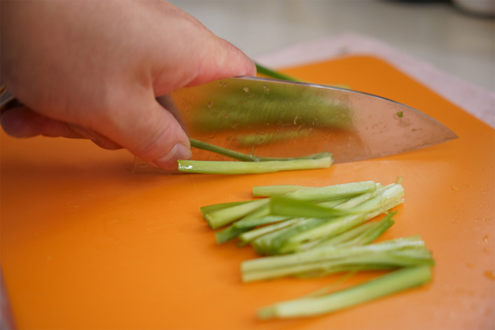 太い茎にも均一に火が入るように、1本ずつ二股部分に包丁を縦に当てて押し切る。このひと手間が大事。その後、茎と葉は分けておく。