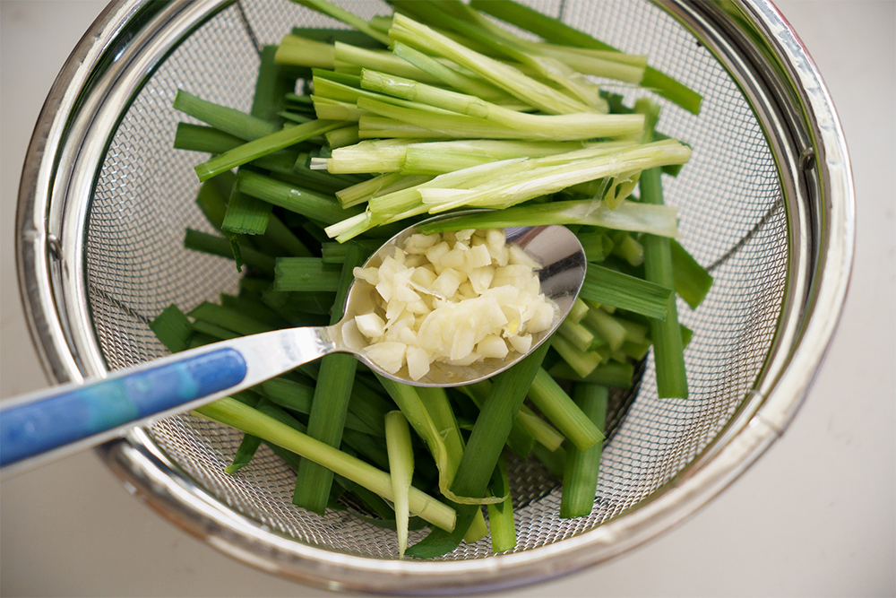ニラは、後から加熱する葉先を下に、先に投入する茎を上にザルに入れておく。ニンニクはスプーンにまとめておくと、加熱時にスムーズ。