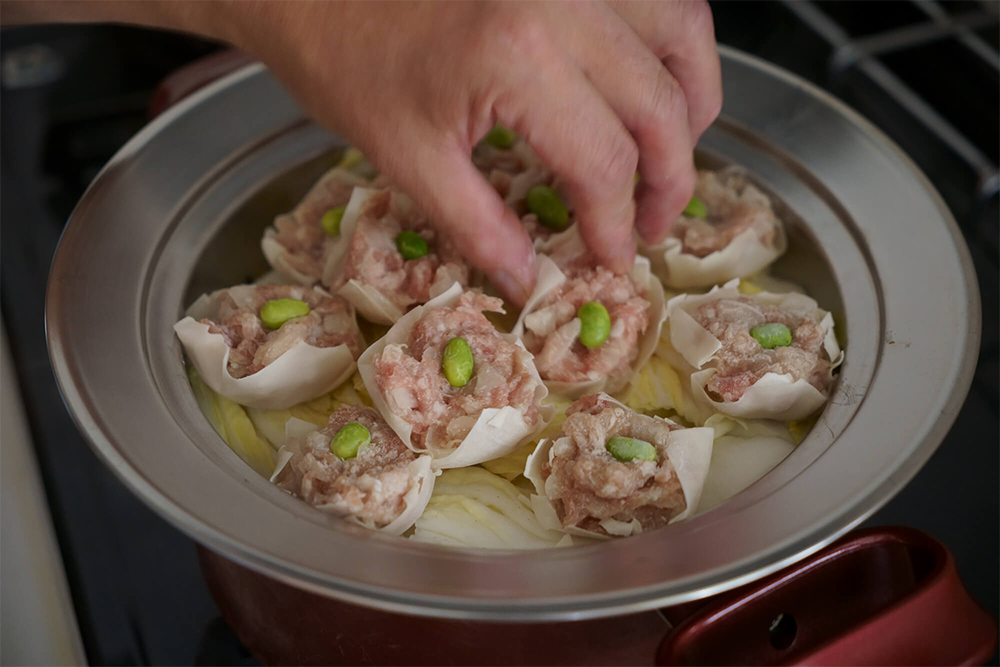 白菜をたっぷり敷いてヘルシーに食べる。そのまま食卓に出せる深めの蒸し器を通販でゲット。ここに大きめにカットした白菜をたっぷりと敷き詰めてから少し蒸し、冷凍したシュウマイをのせて20分蒸す。肉汁が白菜にも染み入る。