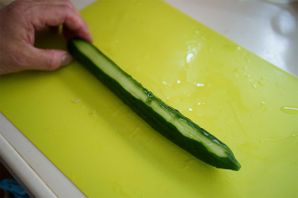 （B）一筋皮を剥いた状態。むいた側を下にしてまな板に置けば転がらない。乱切りするための知恵。