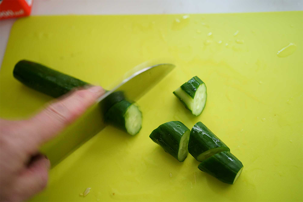 乱切りをスムーズにするコツ 乱切りはキュウリを転がしながら切っていくが、片手ではむずかしい。そこで岡田さんは考えた、「キュウリの皮を一筋むき、その断面を下にしてまな板に置けば固定される」と。その後、約2㎝幅に斜めに包丁を当てて押し切りにする。大きすぎると火が通りにくいので注意。