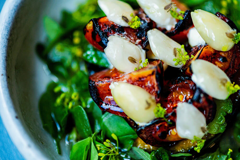 岩牡蠣に重ねた夏野菜の素揚げに、鮮やかなフレッシュハーブを盛り込んだ一皿。