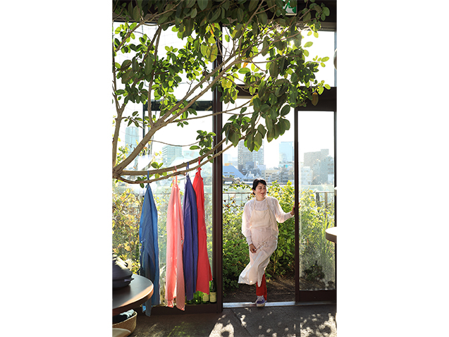 食材を育む 空、太陽、土を感じる場所に ベランダの菜園越しに、渋谷の高層ビル群が見える。時季ごとの花や実で、日の傾きで季節を知ることができるありがたみを、都心だからこそより感じるのだとか。菜園やレストランの庭の果実などで染めたお気に入りのオリジナルエプロンは、販売もしている。