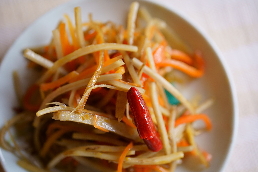 歯ごたえ重視のきんぴら 愛工業のスライサーセット「Ａセット野菜調理器Ｑシリーズ」を購入してから料理の幅が広がった、と岡田さん。きんぴらには「食感も良く、素材の味も感じる」厚さ2.3mm・幅３mmのせん切り用を使う。濃い味ではないが、唐辛子が利いたシャープな味わい。