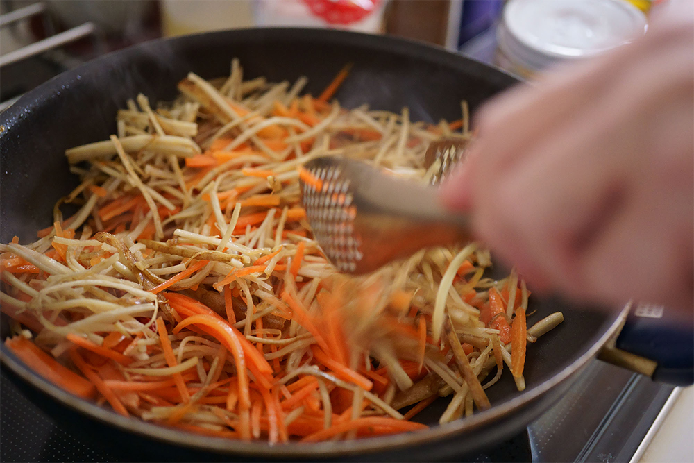 （D）ニンジンは後から加えて歯応えを残す。ニンジンを加えたら中火にして煽る、トングで混ぜるなどして油が回るまで炒める。