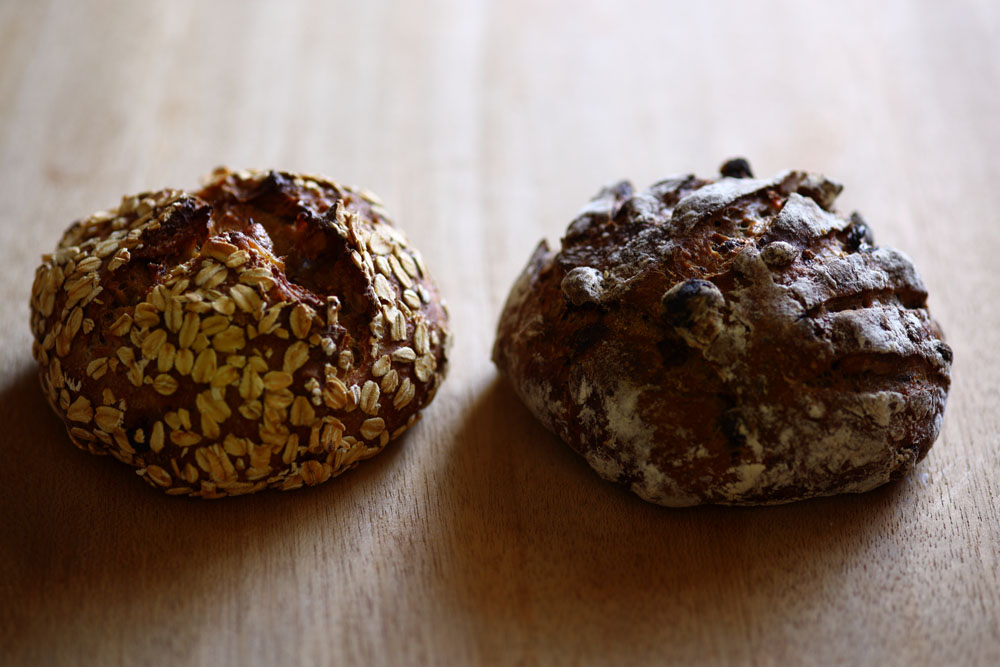 （左）「三種の柑橘フリュイ＆ポリッジ」。柑橘ピール、イチジク、ヘーゼルナッツ、パンプキンシード、熱湯処理した有機オートミールをパン・オ・ルヴァン生地と合わせて。 （右）「紅茶とゴジベリー」は、奄美産黒糖、マッシュポテトを加えて４種の種で発酵させた生地に、クルミ、クコの実、アールグレイなど。すみや農園の有機農林61号の全粒粉を８％使用。