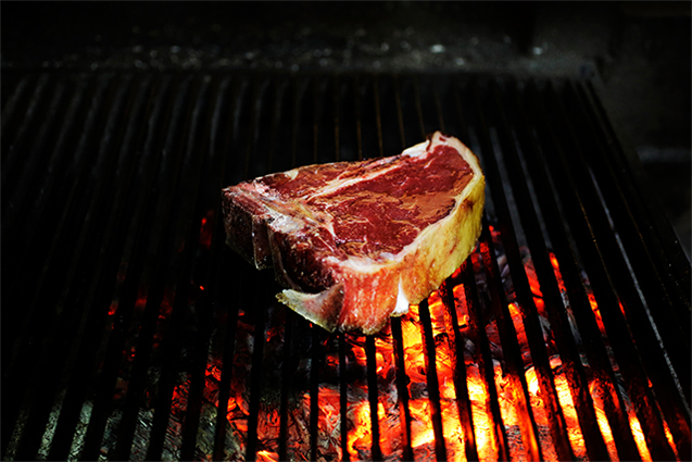 薪火調理は多くの場合、薪を燃やして熾火にしてから食材に火入れする。「ヴァッカロッサ」では、薪を燃やした後、煉瓦で囲わないスペースに熾火を移して火入れする。photograph by Masahiro Goda（写真は アイリッシュグラスフェッドビーフ記事 より）