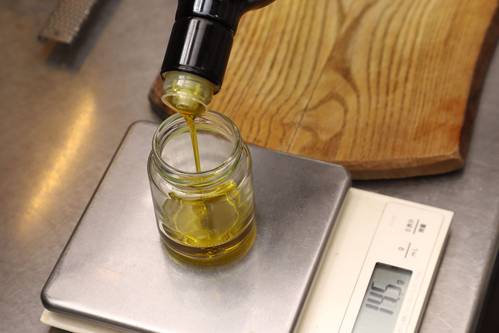 【１】スケールに小瓶をおき、オリーブ油と醤油を計量しながら入れる。