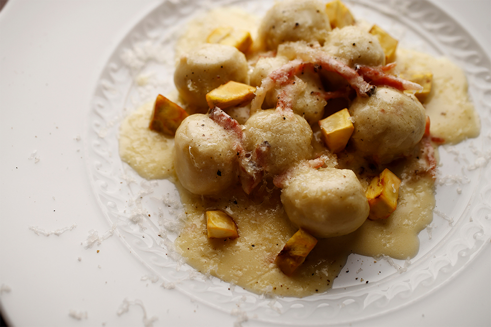 「石鎚とリコッタのマルファッティ　スペックのクリームソース」 蒸して裏漉した石鎚とリコッタチーズに少量の薄力粉を加え、丸く成形したマルファッティ。ヴァルテッリーナ・カゼーラ（牛のセミハードチーズ）とスペックのソースをかけ、石鎚の素揚げを散らす。