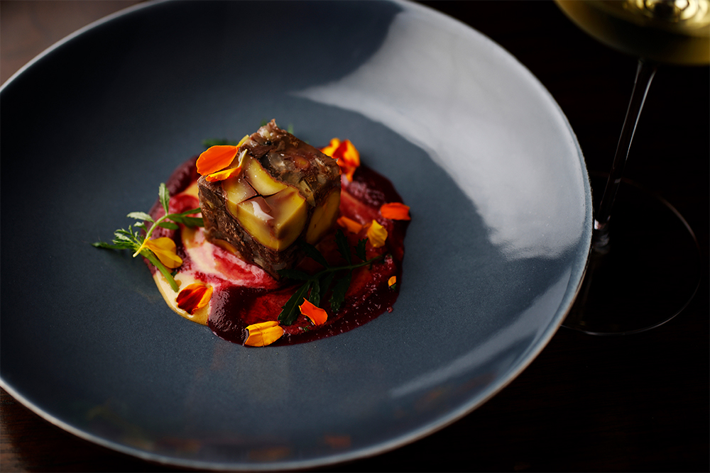 「鹿と飯沼栗のアスピック　バター風味のマヨネーズソースとマリーゴールド」 森をイメージし、じっくり煮込んだ鹿肉とそのスープを、赤ワインを加えた飯沼栗の渋皮煮とともにゼリー寄せに。自家製のマヨネーズは、栗と相性のよいカカオとビーツを加えて色鮮やかに。