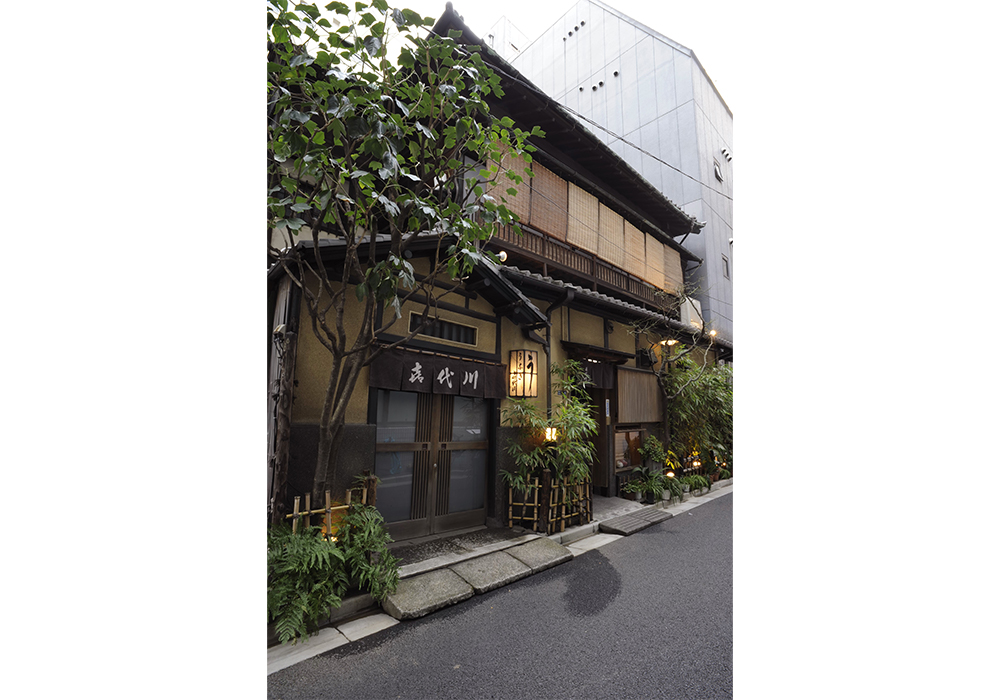 80年を越す数寄屋造りの建物が、ビルの谷間に今もひっそりと建つ。入口は二つあり、手前は2 階の座敷へ、奥がテーブル席の入口となっている。