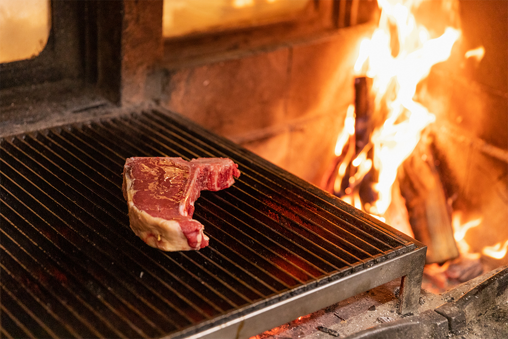 肉を冷蔵庫から出してカット（取材時は700g）、表面にオリーブオイルを塗って、網にのせる。塩はふらない。