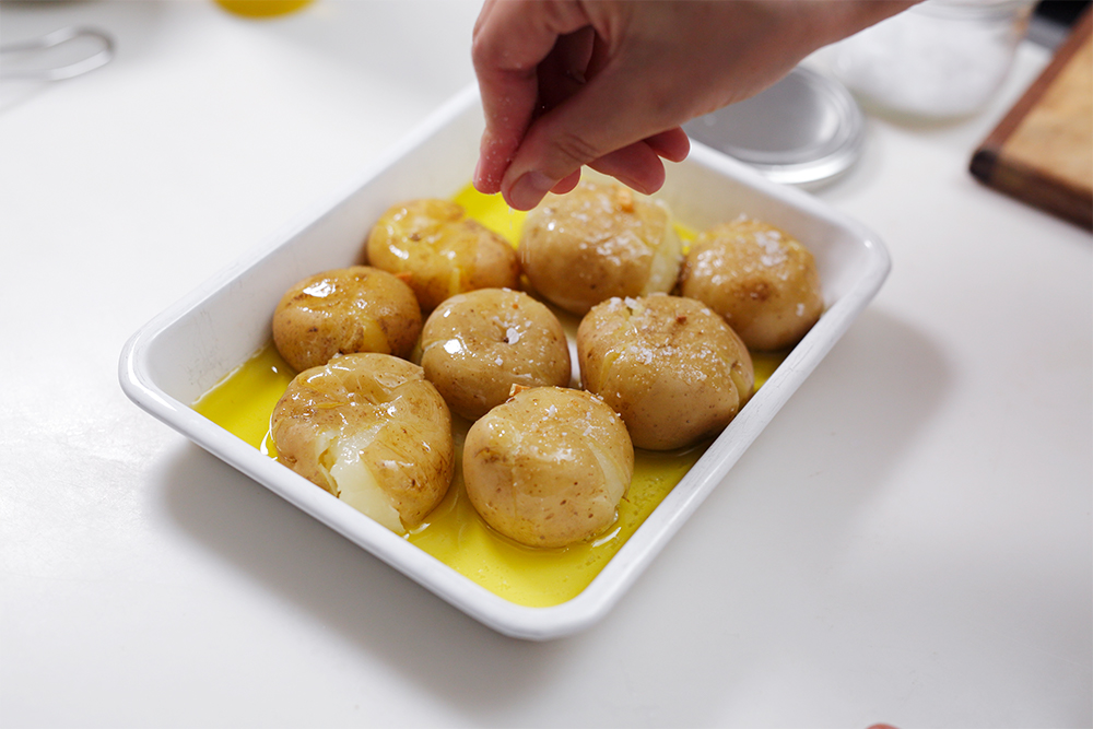 耐熱容器に押し潰したイモを並べ、３のニンニクを煮出したオイルを回しかける。塩を強弱を付けて振る。POINT 油はひたひたに！塩はランダムに！