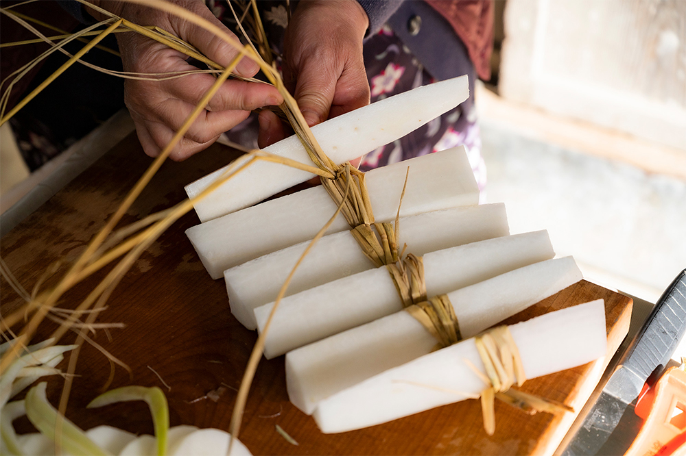 はりはり漬けにする大根は、皮をむかず丸ごと１本を半分に切り、さらに縦に４～６等分に切って紐や縄で結ぶ。