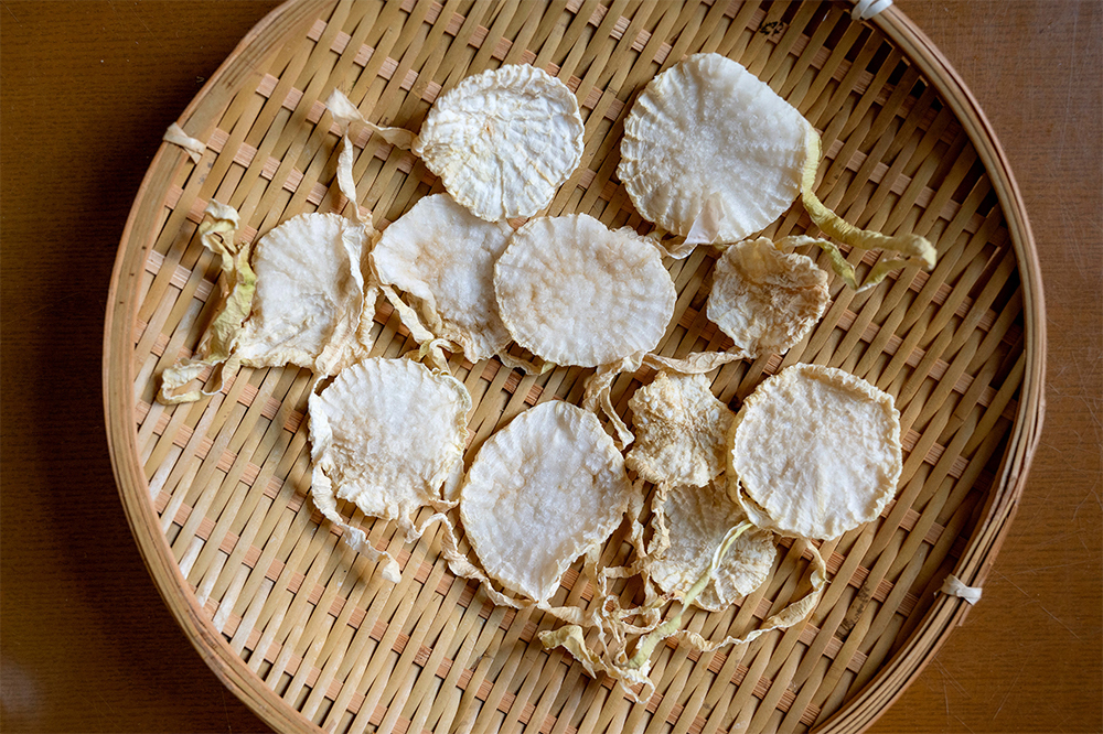 ２． 大根を干す ザルに大根を重ならないように広げ、陽当たり、風通しの良いところで数日干し、カラカラに乾燥させる。直径5㎝程の大きさになる。