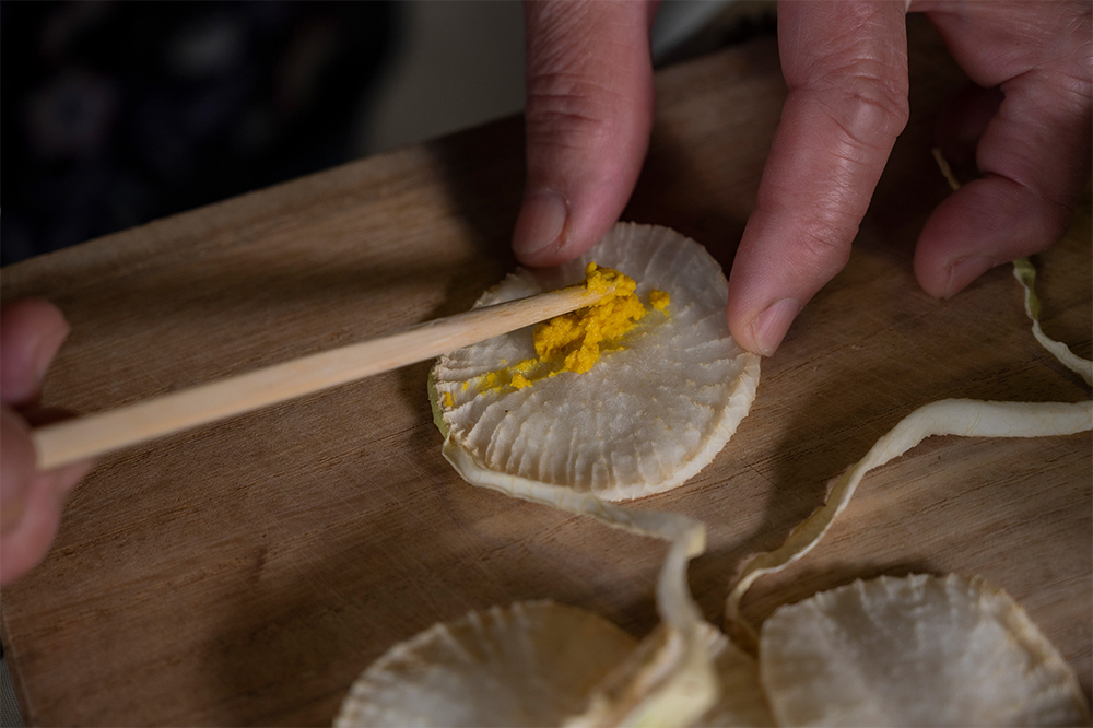 ４． からしを巻く からしを中央に載せ、クルクルと巻く。皮で紐を作った場合、巻き付ける。保存容器に並べる。