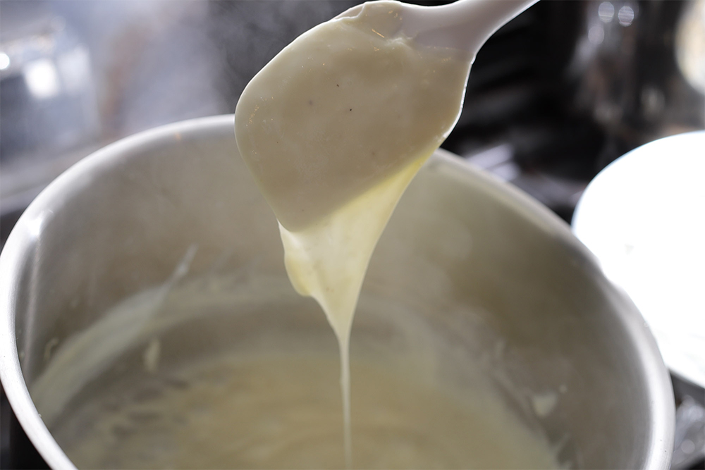 粉っぽさが消えるまで時々ゴムベラで混ぜ、弱火で火を入れる（約10分）。塩、コショウで味を調える。