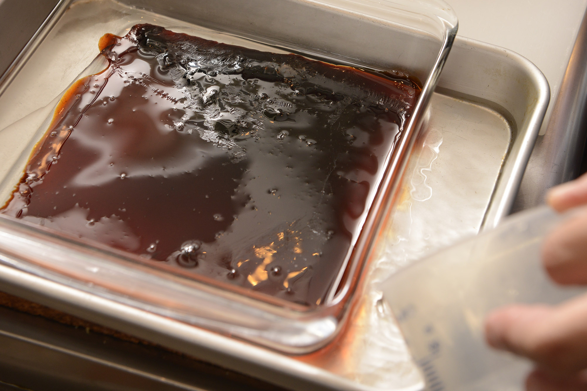 【８】カラメルが固まるよう、プリン型が半分浸かる程度に、バットに水を張る。