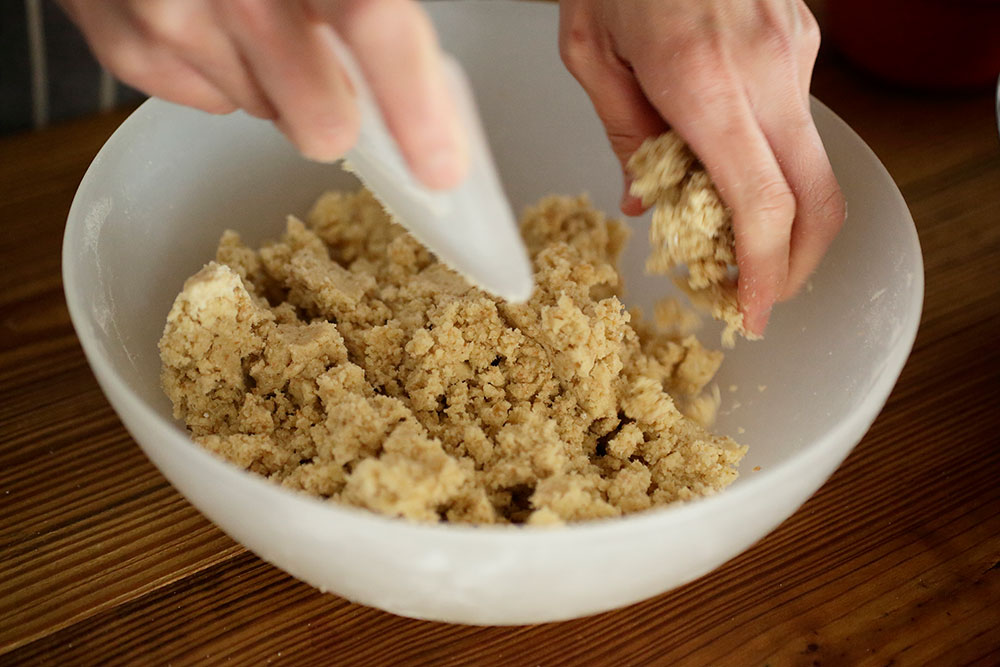 ある程度の大きさの塊ができるまでなじませたら、カードで生地の一部を切り分け、粉っぽいところにのせて軽く押しつける。粉っぽい部分がなくなるまで繰り返す。 POINT:ほろほろした状態で全体をくっつける。 [３]生地を型に敷いて焼く
