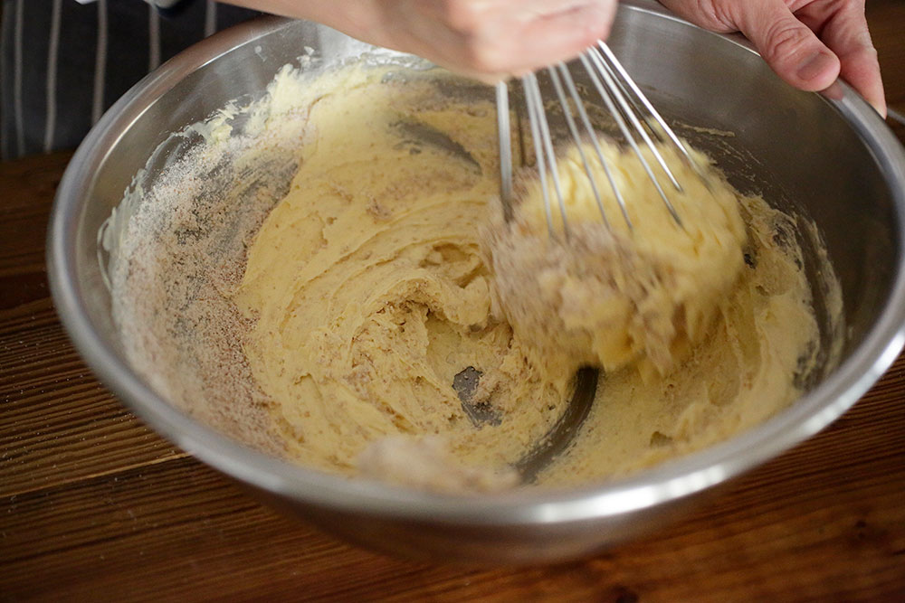 合わせてふるった材料Bの少量を[５]に加え、ホイッパーで混ぜて生地をつなげる。[５]の残りの全卵を加え、小さい円を描くようにしながらやさしく混ぜ合わせて、生地をつなげる。 POINT:果物の水分を支えるため、粉の多い配合に。 [７]粉を加えて混ぜる