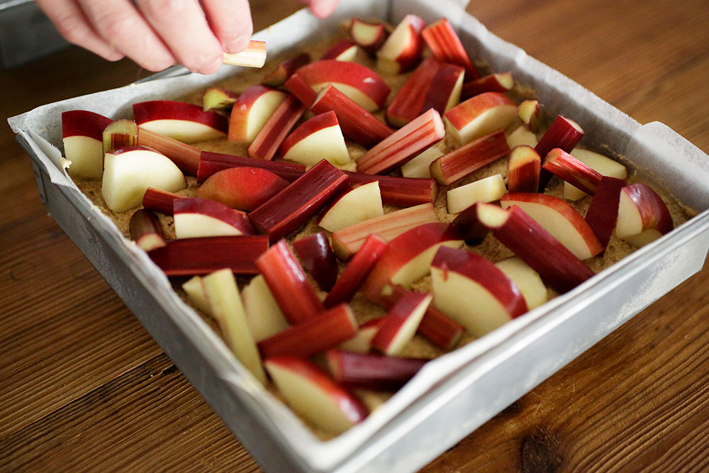 ルバーブは皮の硬い部分を取り除き、長さ４～５㎝に切る。生地に挿すように立てたり寝かせたりしながらリンゴの間にのせる。 [14]クランブルを散らす