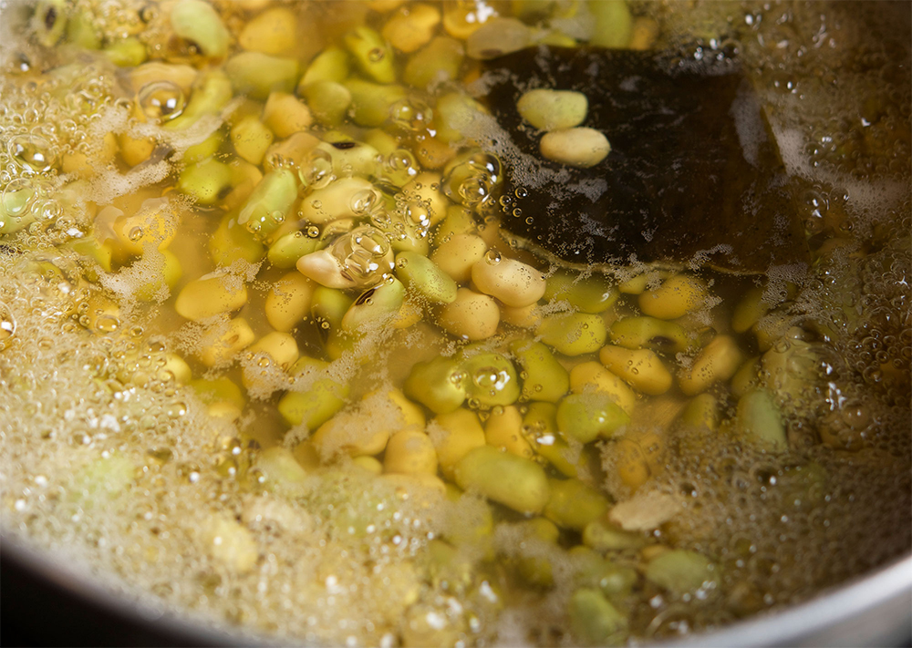 [５]だしで煮る 鍋に豆、だし、昆布、塩、醤油を入れて火にかけ、沸いてきたら火を止めて20〜30分粗熱をとりながら味を含ませる。