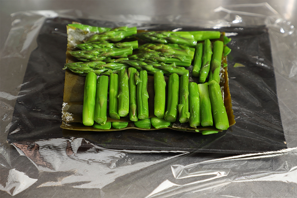 [４]野菜を並べる ラップに昆布を１枚のせてアスパラガスを並べ、昆布をのせる。 POINT：食べるサイズに切って、昆布の面を無駄なく使い、野菜をきれいに敷きつめる。