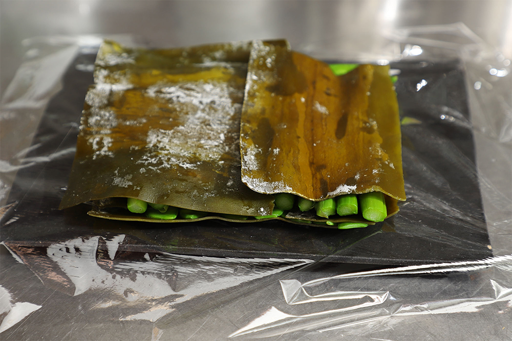 [５]３時間おく そのうえに絹さやを並べ、昆布をのせる。ラップで包み、３時間おく。 POINT：昆布の種類や野菜によって締める時間が変わる。今回は、真昆布と細めの野菜で３時間。