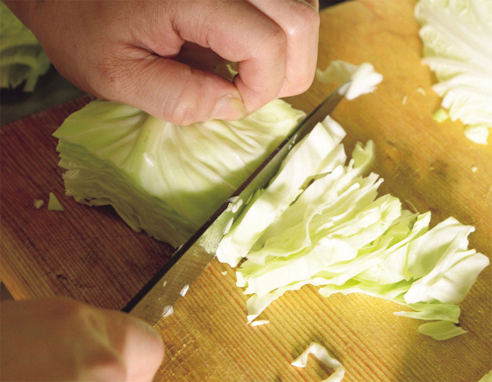 [３]キャベツを切る キャベツを幅１cm弱の細切りにする。 POINT:キャベツは芯のある下半分を使う。