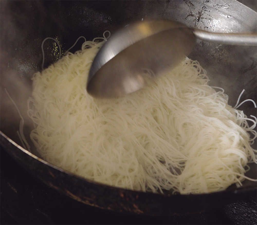 [10]ラードをからめる すぐに中華鍋にビーフンを戻し、ラードを小さじ1/2加えて全体にからめる。