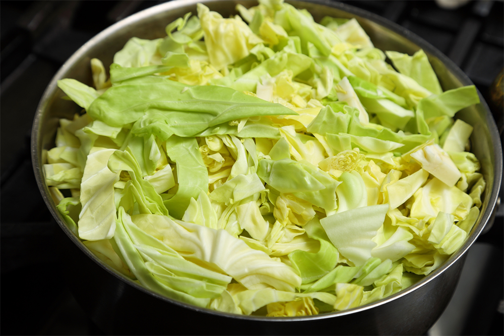 鍋にオリーブ油を入れて全体に広げる。キャベツを山盛りに入れ、塩をふたつまみふってから弱火にかける。 ［３］キャベツに汗をかかせる
