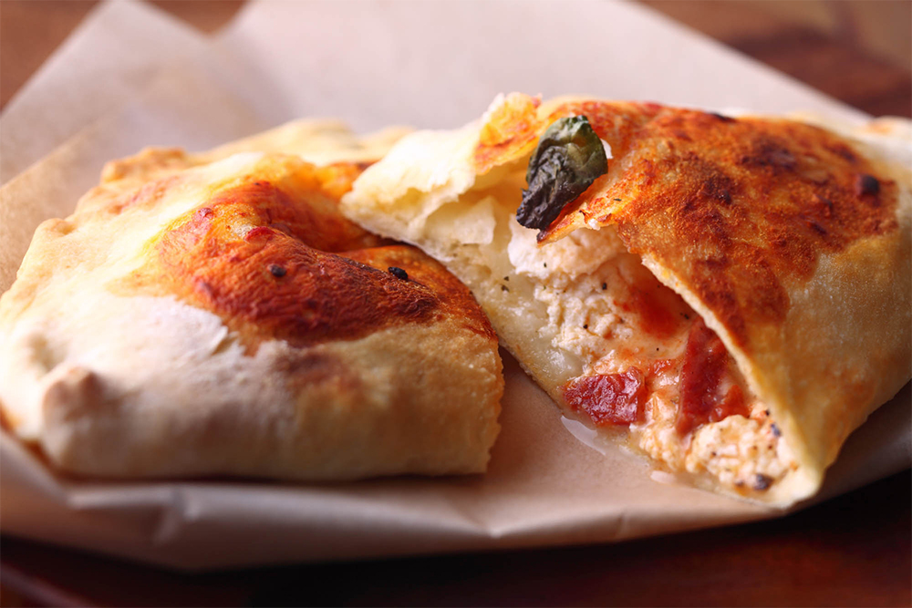 カルツォーネ：リコッタチーズにモッツァレッラ、パルミジャーノを加え、もっちり生地で包んだピッツア。ピリッと辛いサラミが味を引き締める。