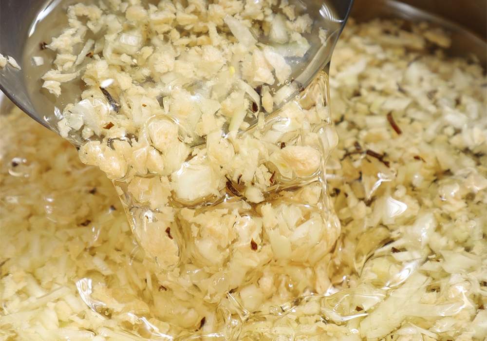 鍋に米油とタマネギ、塩昆布、戻した大豆ミートを入れて玉杓子で混ぜながら中火にかける。 ［２］弱火でじっくり