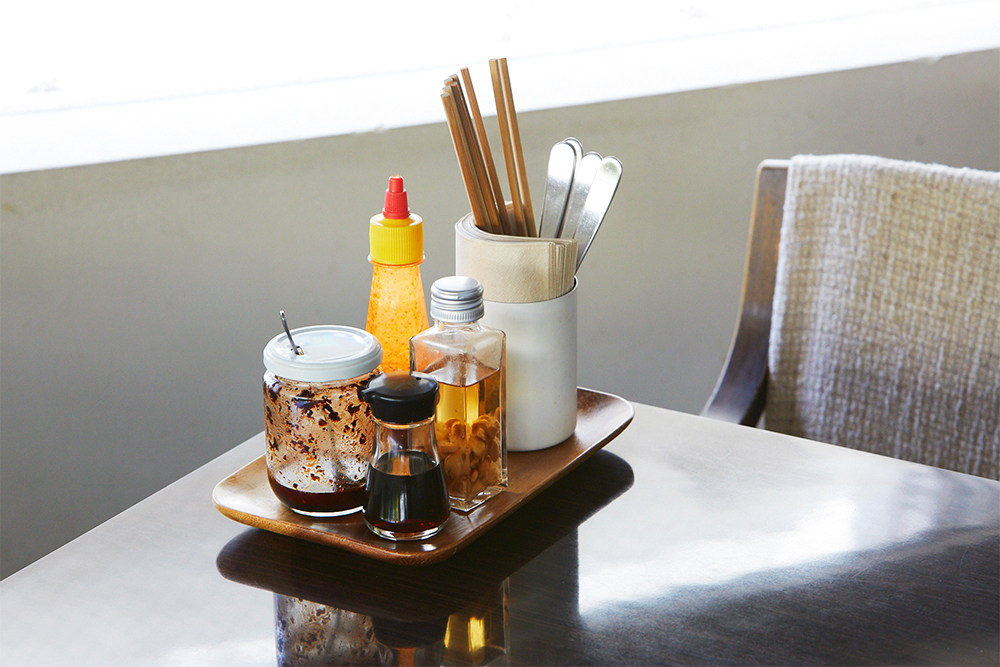 卓上調味料。炒めたニンニクを米酢に浸したニンニク酢やチリオイル、ナンプラー。