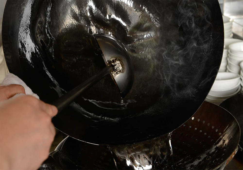 [３] 鍋を油でならす 中華鍋を強火で熱し、サラダ油をお玉１杯弱分入れて、表面を油でならしたら、捨てる。新しいサラダ油を大さじ２加え、弱火に落とす。