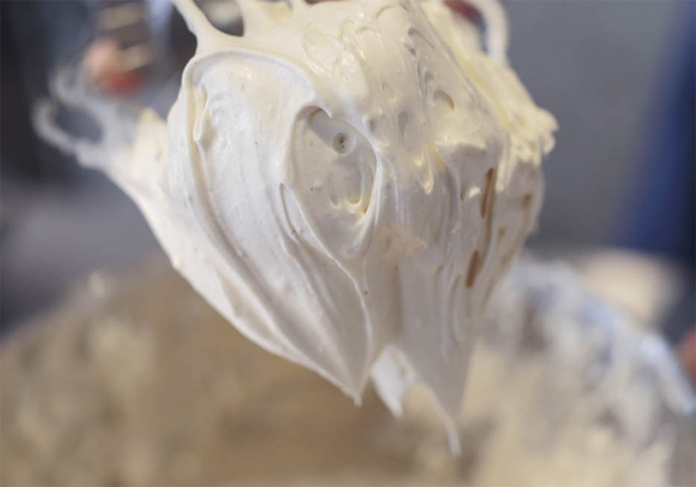 [４]角が立つまで混ぜる 低速→中速へと徐々に上げながら混ぜ合わせる。分離しないよう注意する。写真のように生地に艶が出てふわっと角が立てばOK。