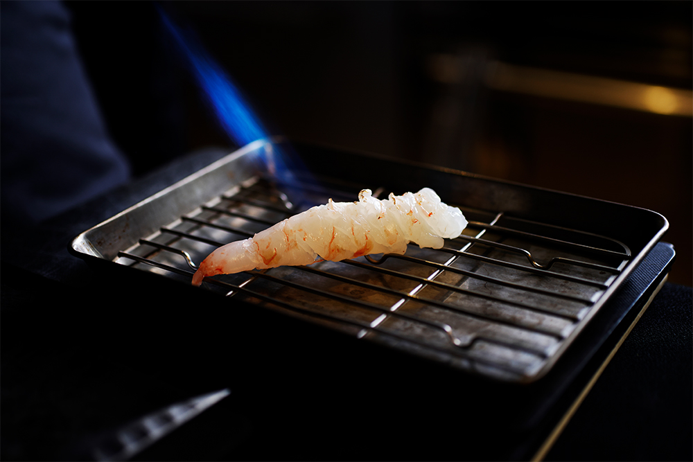ボタン海老は「ねっちりした食感を、グリーンピースのプチプチした歯ざわりと合わせるのが面白いかな、と考えて」と加瀬シェフ。バーナーで軽く炙ることで、香ばしさが立つ。