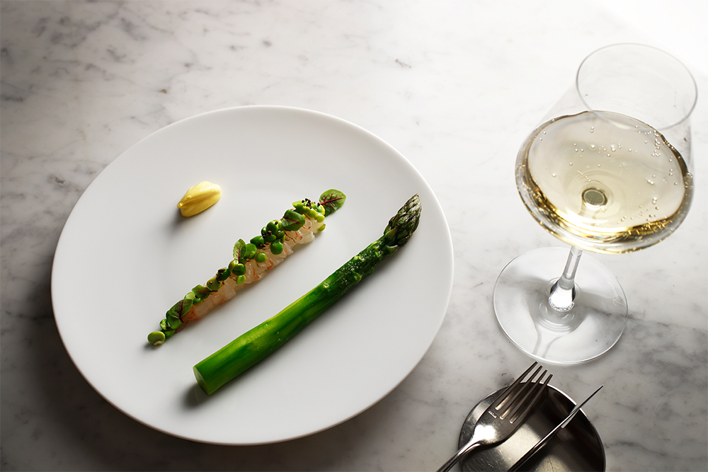 香りを閉じ込めたグリーンアスパラガスのボイル、表面を軽く炙ったボタンえびとグリーンピースのタルタルで構成するシンプルな前菜。ターメリック、ライム、シャルトリューズを練り込んだサワークリームを付け合わせに添え、“味変”を楽しめる仕立てに。