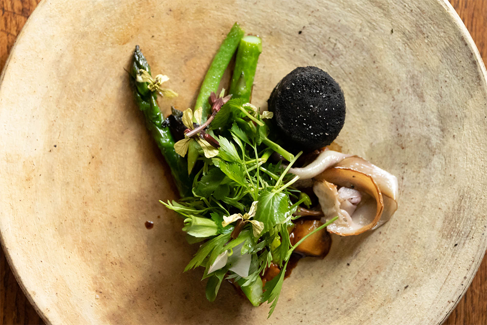 [アスパラ　行者ニンニク　ごぼう、豚足] こっくりと煮込まれ、ゼラチン質の弾力とやわらかさが引き出された豚足と、グリーンアスパラの風味、ゴボウの土臭さを練り込んだケークサレが一体となり、フィニッシュにふさわしい力強さを演出。甘味、酸味、苦味、食感が、それぞれくっきりとした輪郭を持つ。