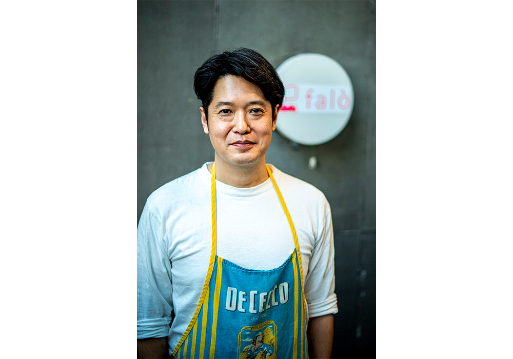 1994年より日髙良実シェフの下で研鑽を積み、「マンジャ ペッシェ」「アクアパッツァ」のシェフを務め、2016年、炭火焼イタリアンと自然派イタリアワインの店「falò」のシェフに。炭火を使って肉や魚、季節の野菜をシンプルに焼き上げる。焼き台の前に鉢巻き姿で立つのは「お客さんに肩肘張らず気軽に楽しんでほしくて、炉端焼き屋を思わせるこのスタイルに」。釣り好き。