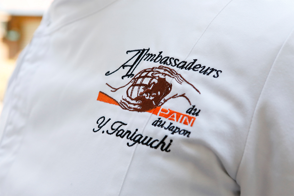 レ・アンバサドゥール・デュ・パンのマーク。手から手へ伝えていく精神を描いている。